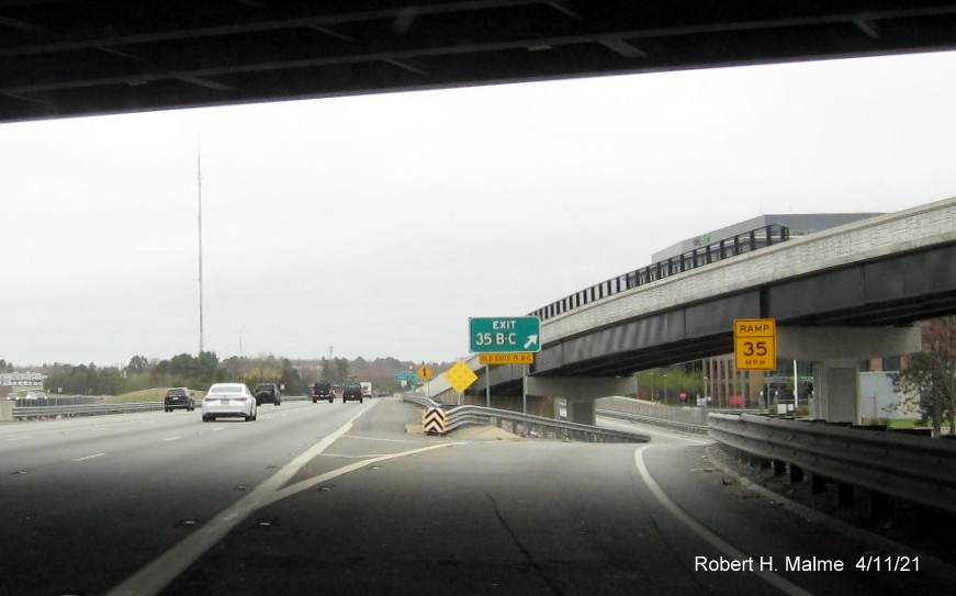 Image of gore sign for Highland Avenue exits with new milepost 
                                            based exit numbers on I-95/MA 128 North in Needham, April 2021