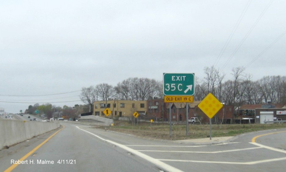 Image of gore sign for Highland Avenue West exit with new milepost 
                                            based exit numbers and yellow Old Exit 19 C sign attached below on C/D ramp from I-95/MA 128 North in Needham, April 2021