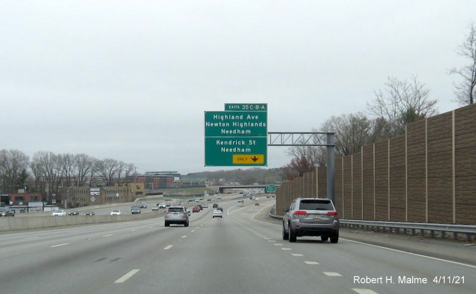 Image of overhead C/D ramp sign for Highland Avenue/Kendrick Street exits with new milepost based 
                                            exit numbers on I-95/MA 128 South in Needham, April 2021