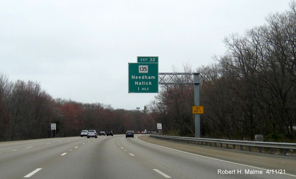 Image of 1 Mile advance overhead sign for MA 135 exit with new milepost based exit number and yellow 
                                           Old Exit 17 advisory sign on support on I-95/MA 128 North in Dedham, April 2021