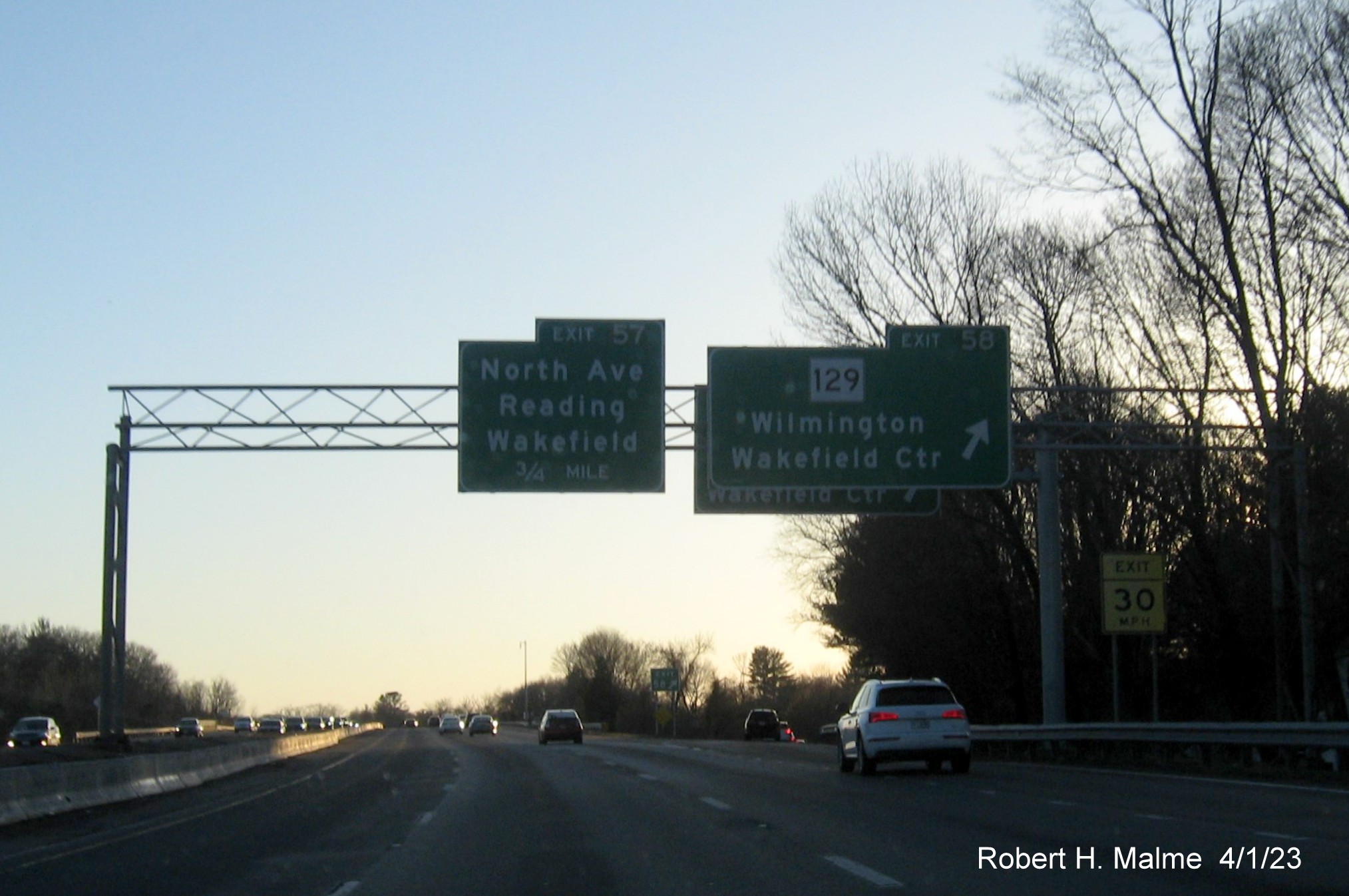 Image of recently placed overhead ramp sign for MA 129 exit hidden behind existing signage on I-95/MA 128 South in Wakefield, April 2023