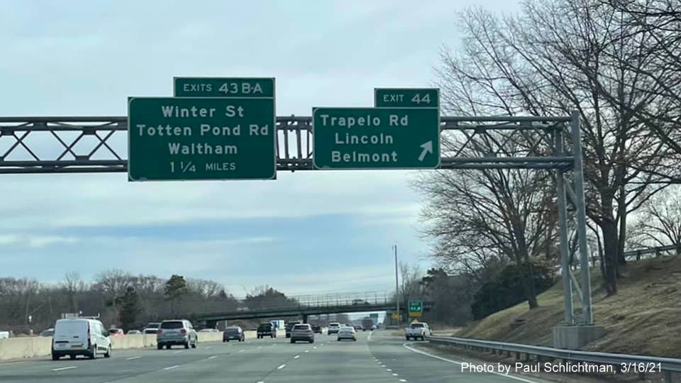 Image of overhead ramp sign for the Trapelo Road exit with new milepost based exit number and yellow Old Exit 28 sign on right support on I-95/MA 128 South in Lexington, photo by Paul Schlictman, March 2021