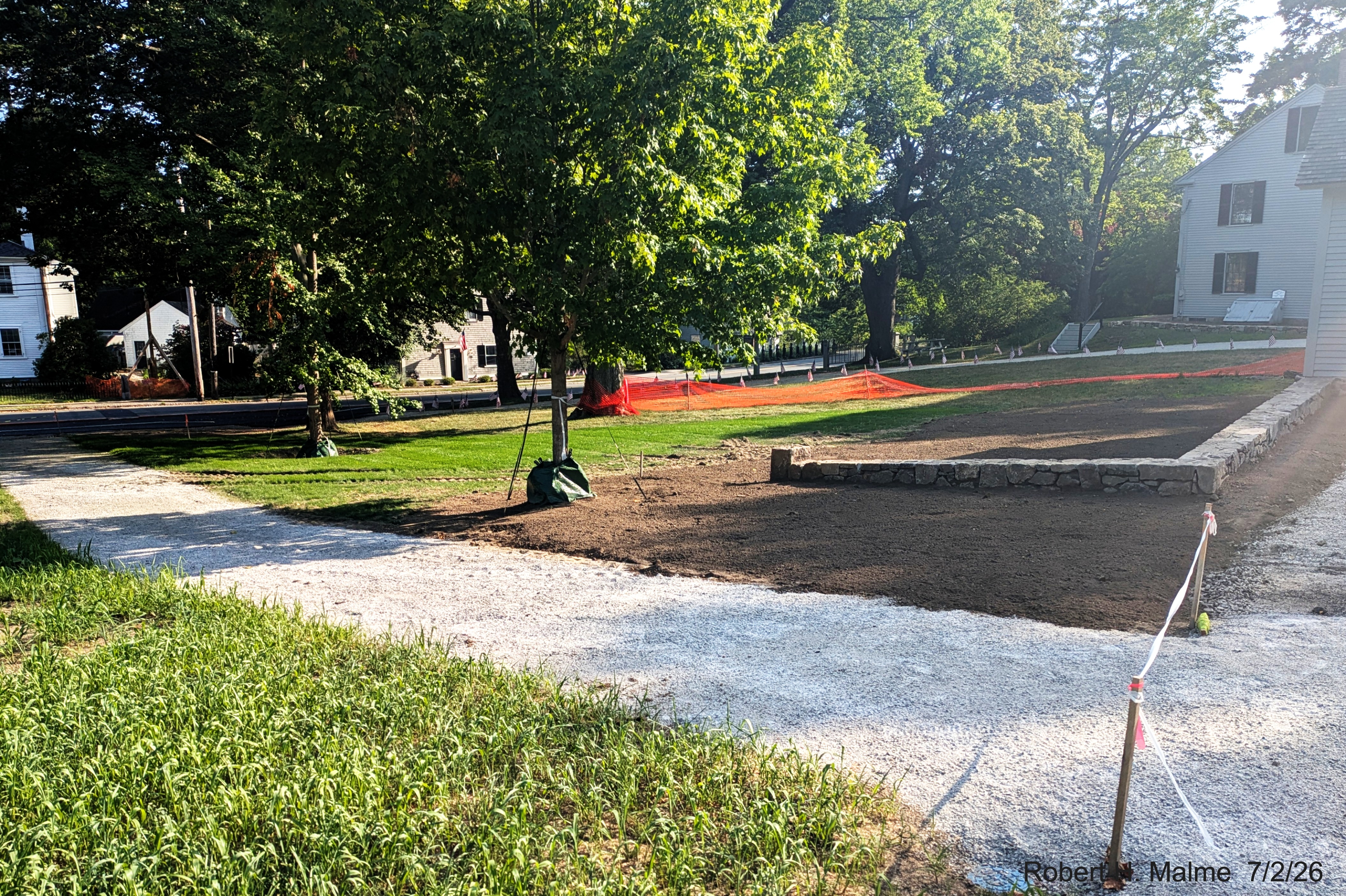 Image taken looking across Lincoln Street toward completed rock wall next to walking
	path in front of the Benjamin Lincoln House, July 2026