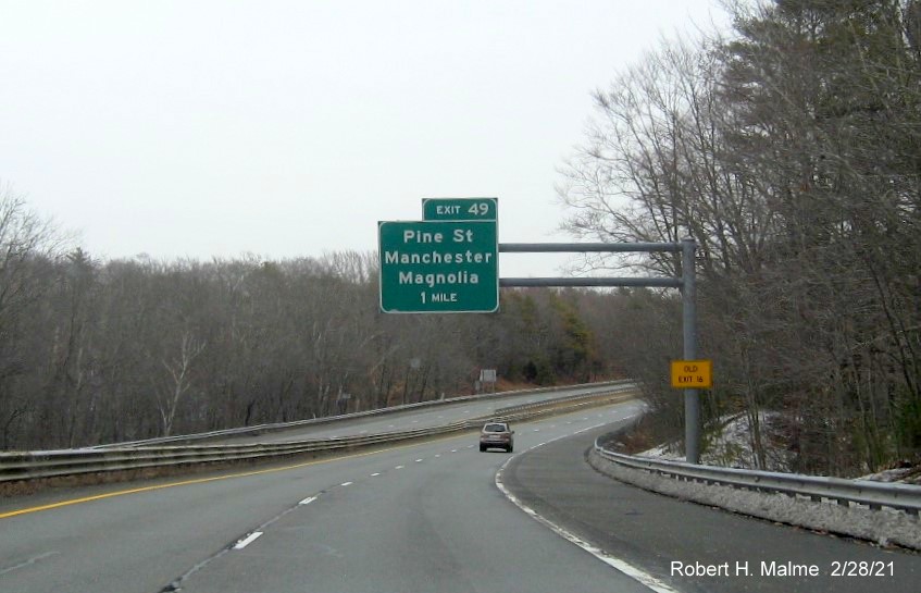 Image of 1 mile advance overhead sign for Pine Street exit with new milepost based exit number and yellow old exit number sign on support post on MA 128 North in Manchester-by-the-Sea, February 2021