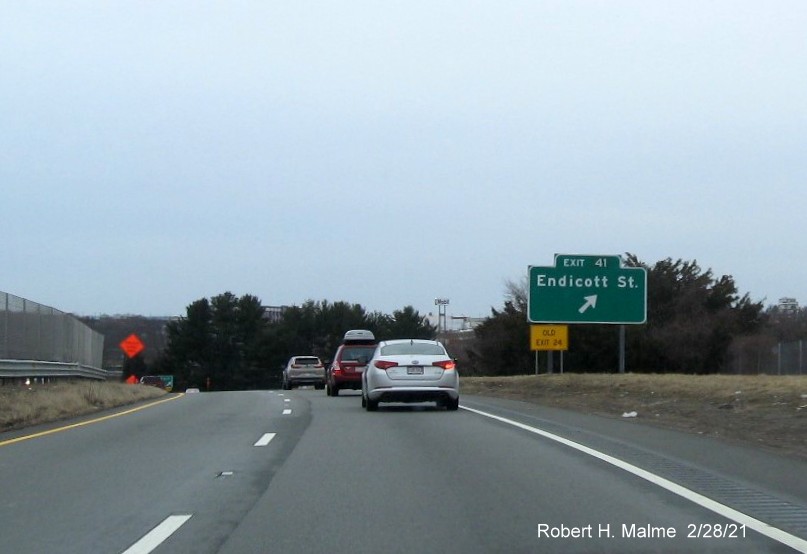 Image of ground mounted ramp sign for the Endicott Street exit with new milepost 
      based exit number and yellow old exit sign in front of the sign on MA 128 South in Danvers, February 2021