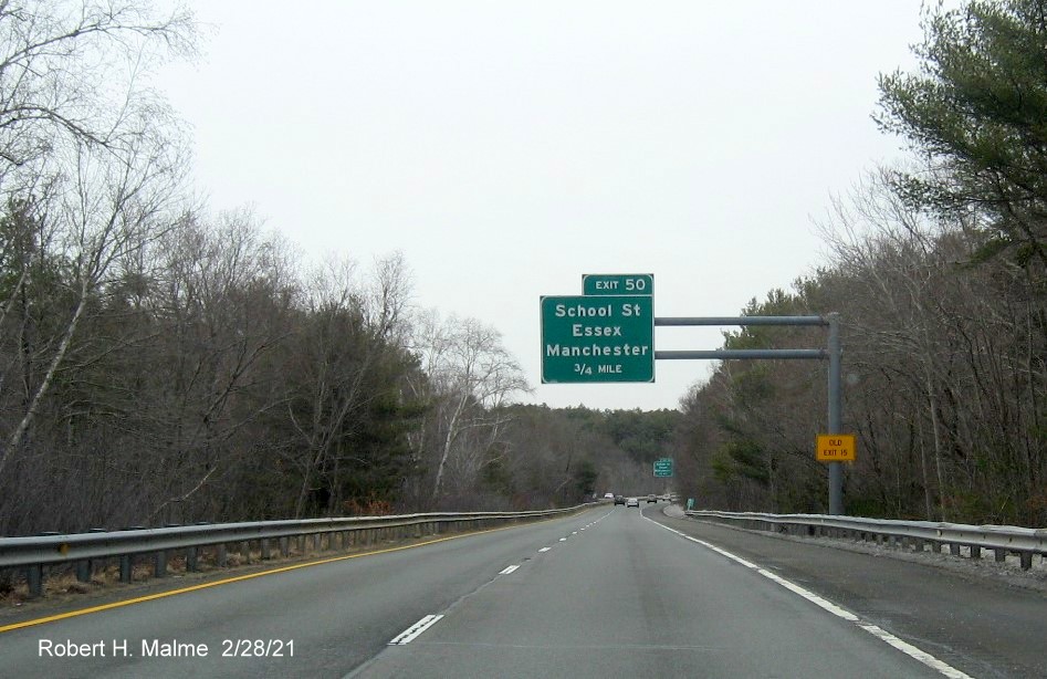 Image of 1 mile advance overhead sign for School Street exit with new milepost based exit number and yellow old exit number sign on support post on MA 128 North in Essex, February 2021