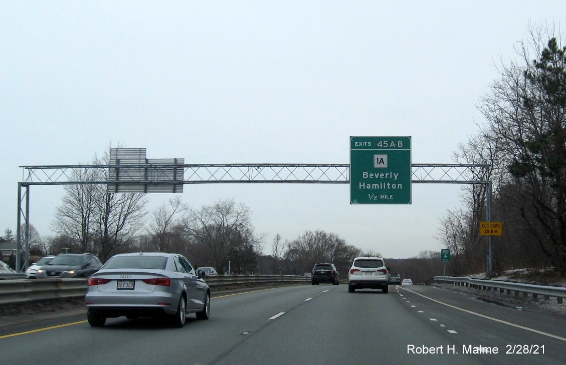 Image of 1/2 mile advance sign for MA 1A exits with new milepost based exit numbers and yellow old exit number sign on support post on MA 128 North in Beverly, February 2021