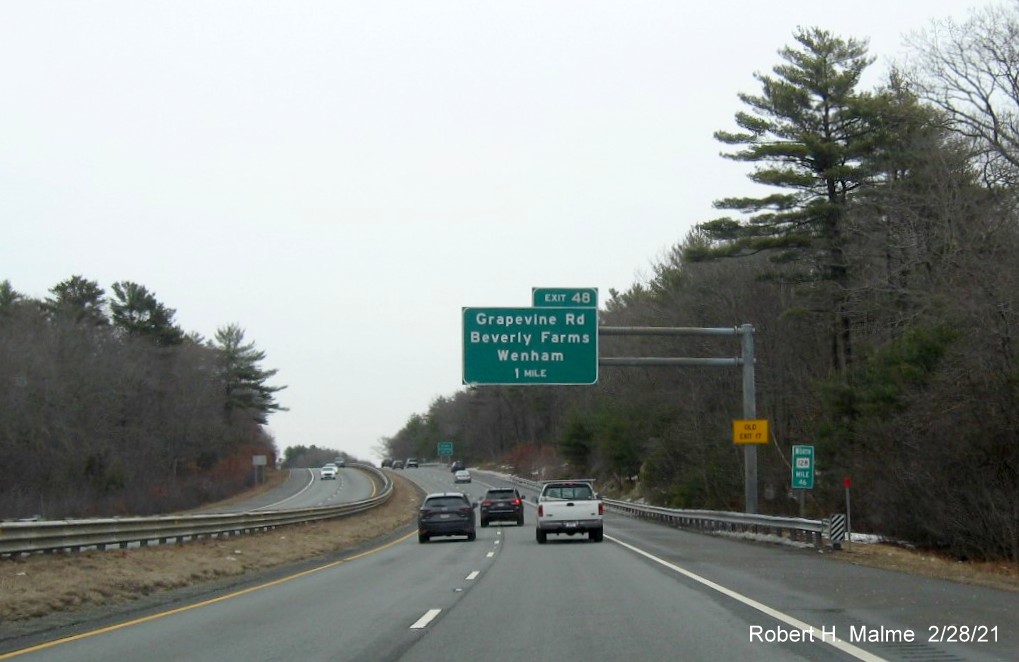 Image of 1 mile advance overhead sign for Grapevine Road exit with new milepost based exit number and yellow old exit number sign on support post on MA 128 North in Wenham, February 2021