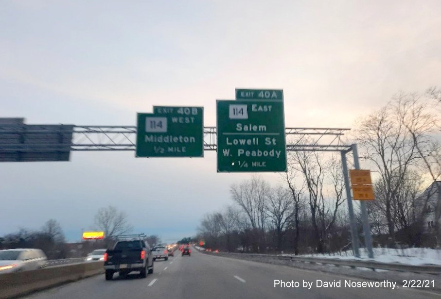 Image of overhead advance signs for MA 114 exits with new milepost based exit number and yellow old exit number signs on right support post on MA 128 North in Peabody, photo by David Noseworthy, February 2021