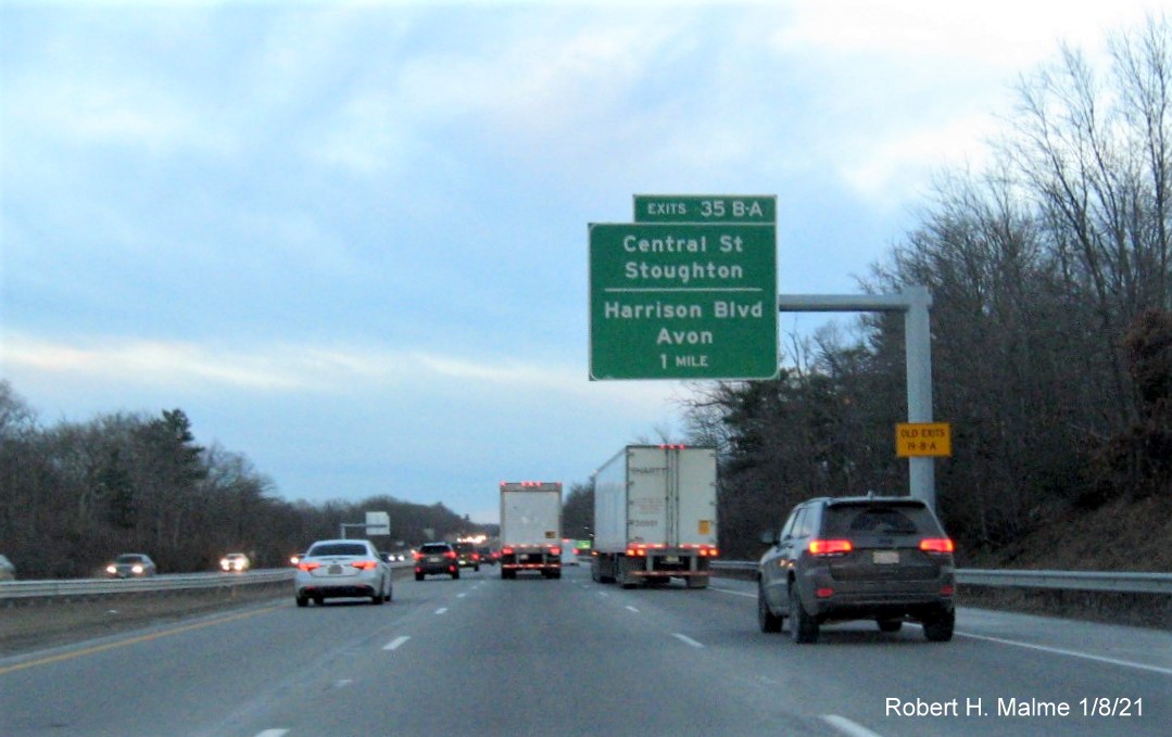 Image of 1 mile advance overhead sign for Central St./Harrison Blvd. exits with new milepost based exit number 
                                      and yellow old exit number sign on support post on MA 24 South in Avon, January 2021