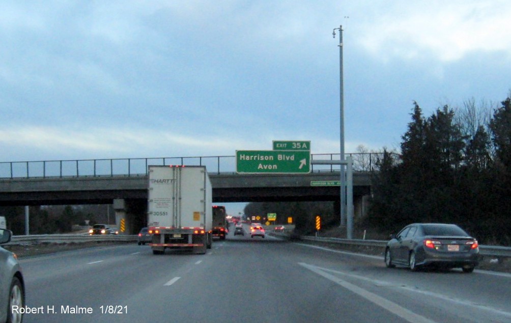 Image of overhead ramp sign for Harrison Blvd. exit with new milepost based exit number 
                                      and gore sign with yellow old exit number sign below on MA 24 South in Canton, January 2021