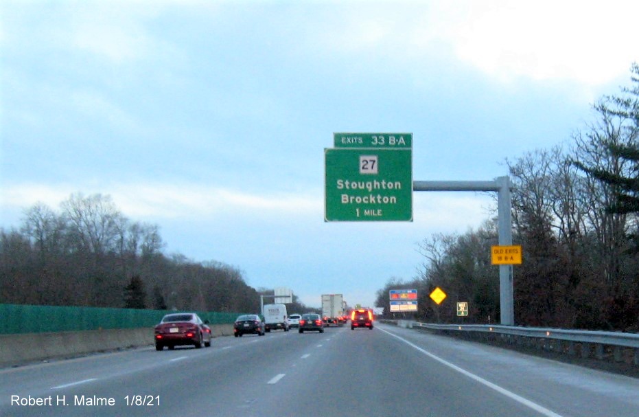 Image of 1 mile advance overhead sign for MA 27 exits with new milepost based exit number 
                                      and yellow old exit number sign on support post on MA 24 South in Brockton, January 2021