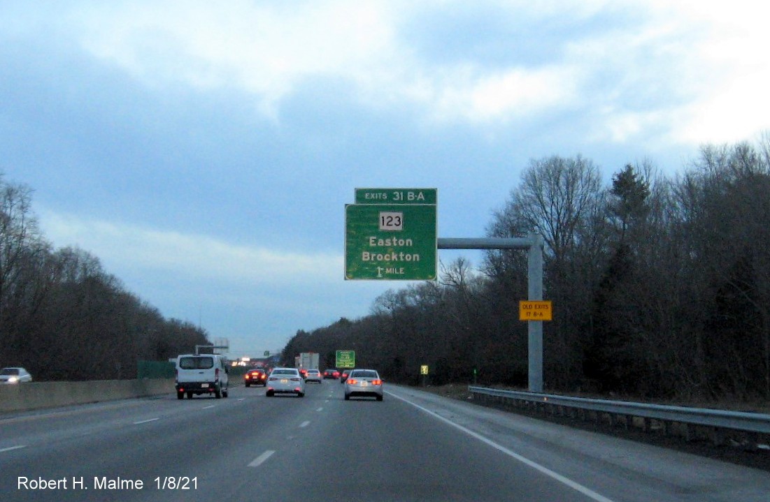 Image of 1 mile advance overhead sign for MA 123 exits with new milepost based exit number 
                                      and yellow old exit number sign on support post on MA 24 South in Brockton, January 2021