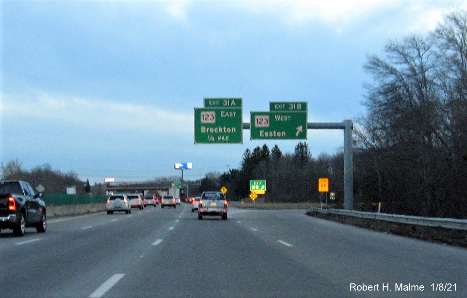 Image of overhead signs at ramp for MA 123 West exit with new milepost based exit number 
                                      and gore sign with yellow old exit number sign below on MA 24 South in Brockton, January 2021