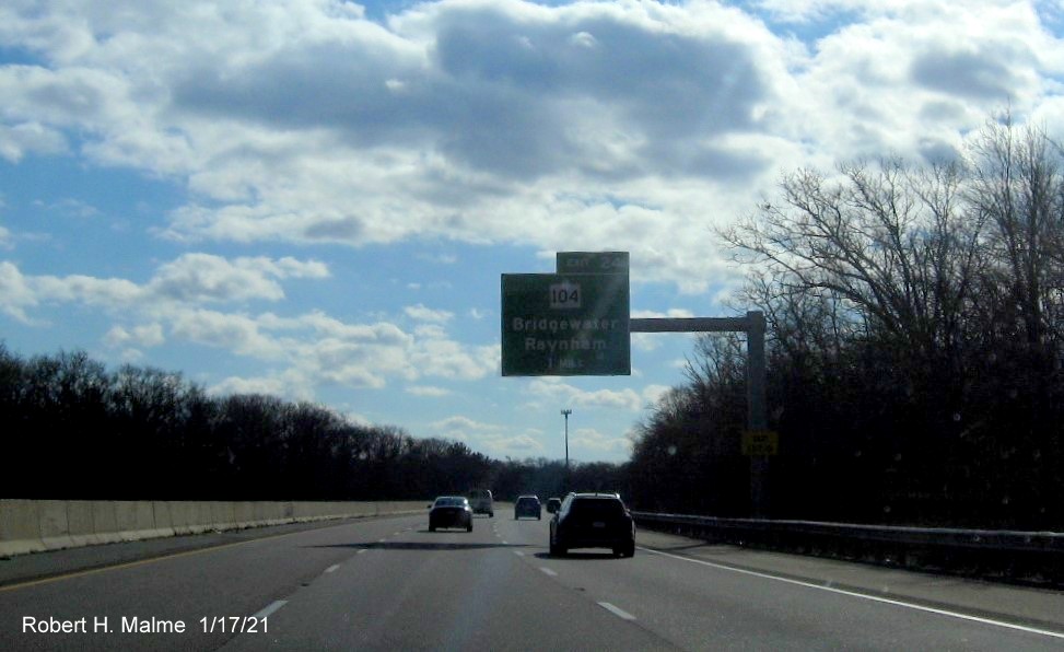 Image of 1-Mile advance overhead sign for MA 104 exit with new milepost based exit number and yellow Old Exit 15 sign on support post on MA 24 South in Bridgewater, January 2021
