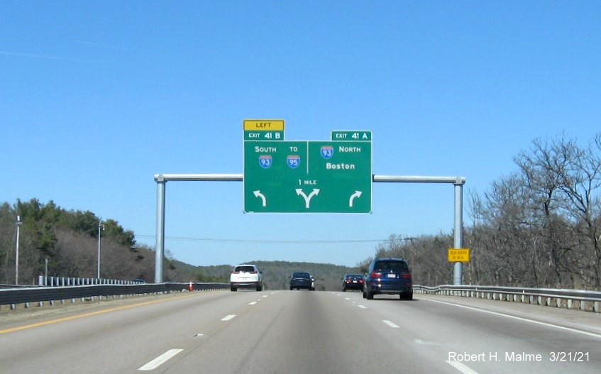 Image of 1 mile advance arrow-per-lane change recently placed on MA 24 North in Randolph with new milepost based exit numbers and yellow Old Exits 21 B-A advisory sign on right support, March 2021