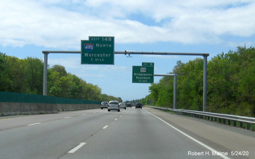 Image of recently placed 1/2 mile advance overhead sign behind sign gantry with former sign still with 1 mile advance sign for I-495 exit on MA 24 South in Bridgewater