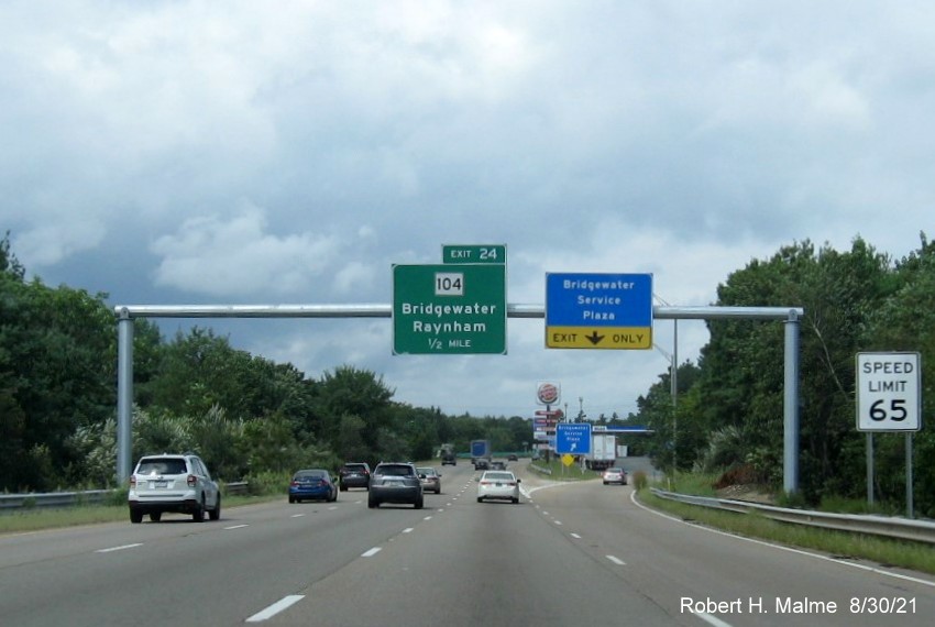 Image of newly placed 1/2 mile advance overhead sign for MA 104 exit sharing gantry with Service Area sign with new milepost based exit number on MA 24 North in Bridgewater, July 2021