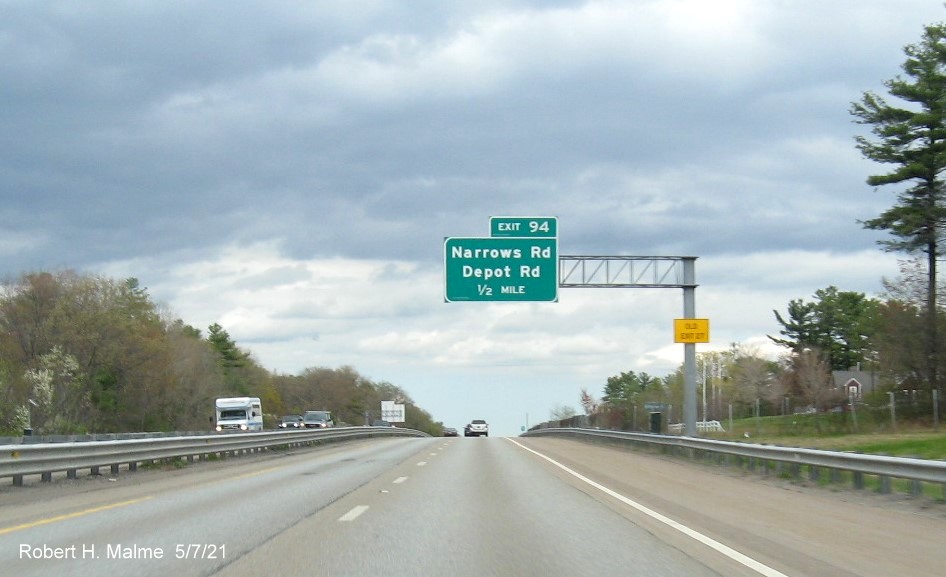 Image of 1/2 mile advance overhead sign for Narrows Road/Depot Road exit with new milepost based exit number and yellow Old Exit 27 advisory sign on support on MA 2 East in Fitchburg, May 2021