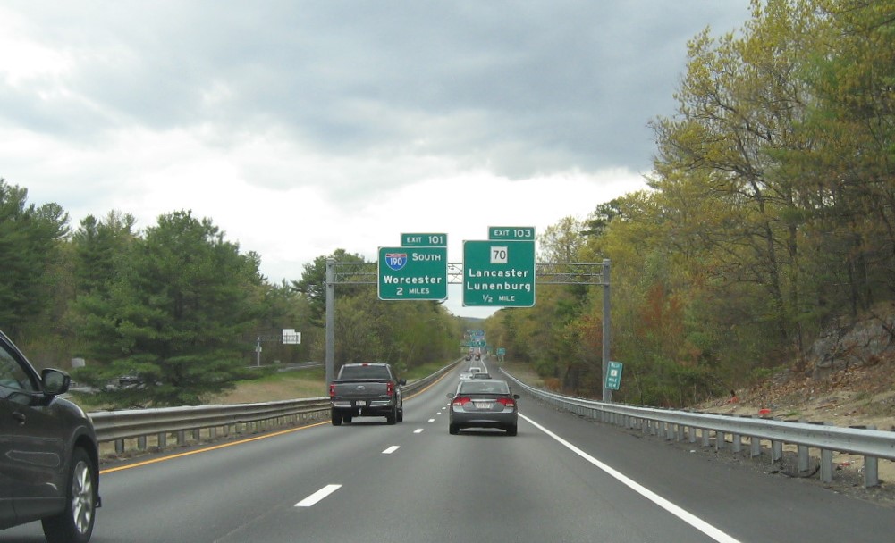 Image of 1 mile advance overhead sign for MA 70 exit with new milepost based exit number and yellow Old Exit 35 advisory sign on support on MA 2 East in Lancaster, May 2021