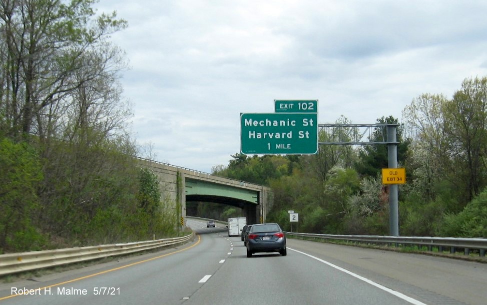 Image of 1 mile advance overhead sign for Mechanic Street exit with new milepost based exit number and yellow Old Exit 34 advisory sign on support on MA 2 East in Leominster, May 2021