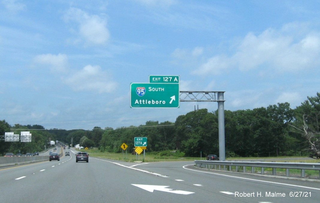 Image of overhead ramp sign for I-95/MA 128 South exit with new milepost based exit numbers and gore sign with new number and yellow Old Exit 52 A advisory sign below on MA 2 West in Lexington, June 2021