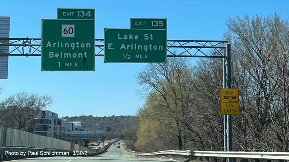 Image of overhead advance signs for MA 60 and Lake Street exits with new milepost based exit numbers and yellow Old Exit 60 and 59 advisory signs on right support on MA 2 West in Arlington, by Paul Schlichtman, March 2021