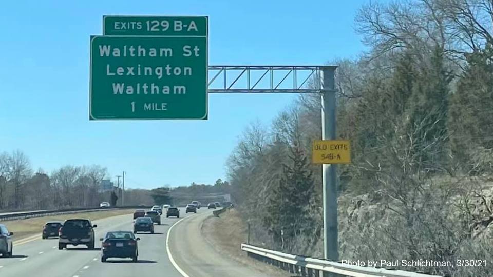 Image of 1 Mile advance overhead sign for Waltham Street exits with new milepost based exit numbers and yellow Old Exit 54 advisory sign on support on MA 2 West in Lexington, by Paul Schlichtman, March 2021