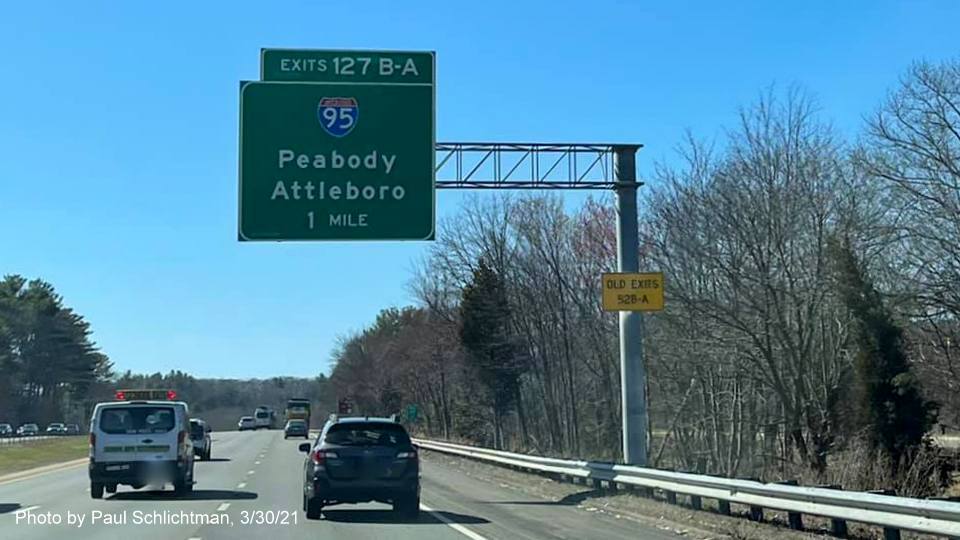 Image of 1 Mile advance overhead sign for I-95/MA 128 exits with new milepost based exit numbers and yellow Old Exits 52 B-A advisory sign on left support post on MA 2 West in Lexington, by Paul Schlichtman, March 2021