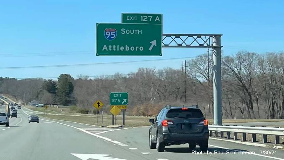 Image of overhead ramp sign for I-95/MA 128 South exit with new milepost based exit numbers and gore sign with new number and yellow Old Exit 52 A advisory sign below on MA 2 West in Lexington, June 2021