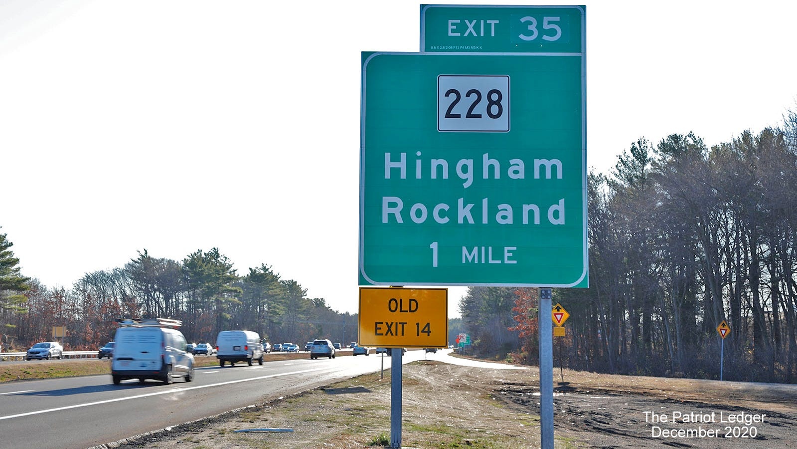 Image taken by the Patriot Ledger of 1-Mile advance sign for MA 228 exit with new milepost based exit number and yellow old exit number sign on left support on MA 3 South in Hingham, December 2020