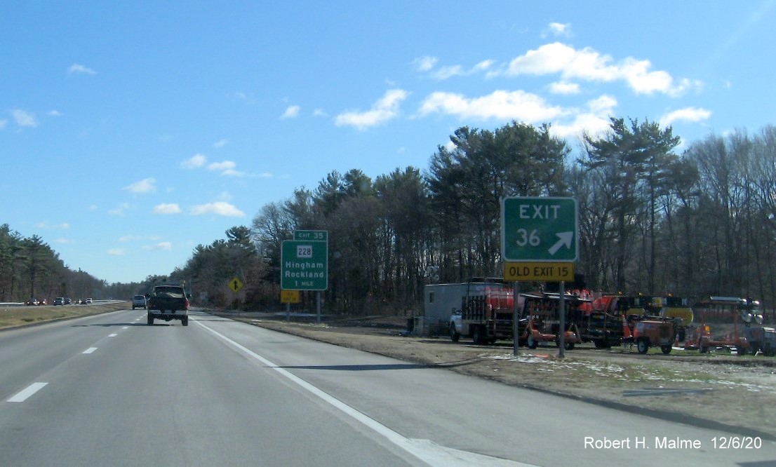 Image of gore sign for Derby Street exit with new milepost based exit number and yellow old exit tab below plus 1 mile advance sign for MA 228 exit also with new exit number and old exit number sign onl left support post on MA 3 South in Hingham, December 2020