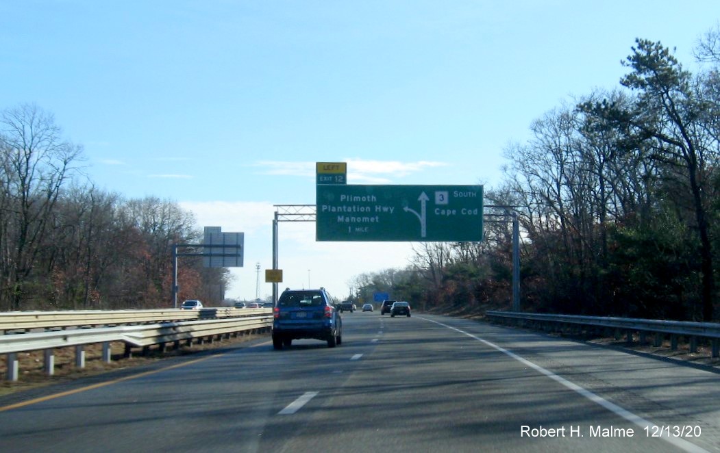 Image of 1-mile advance overhead diagrammatic sign for Plimoth Plantation Highway exit with new milepost based exit number and yellow old exit number sign on left support on MA 3 South in Plymouth, December 2020