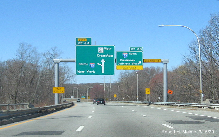 Image of overhead signage at ramp to I-95 North on RI 37 West in Cranston with new exit numbers and old exit number tabs placed on support posts, taken in March 2020