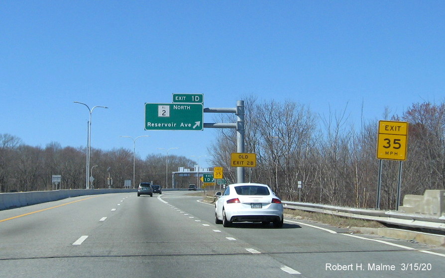 Image of overhead ramp sign for RI 2 North on RI 37 West in Cranston with new exit number and old exit number sign on support post, taken in March 2020