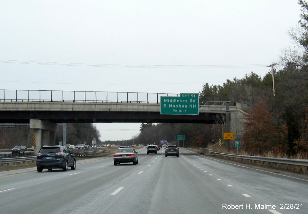 Image of 1/2 mile advance overhead sign for Middlesex Road exit with new milepost based exit number and yellow old exit number sign on support on US 3 North in Tyngsborough, February 2021