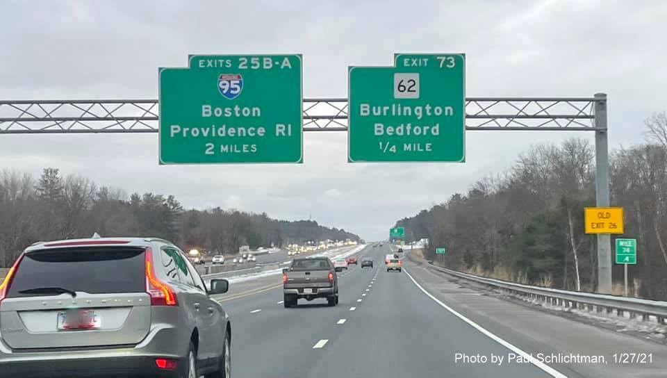 Image of 1/4 mile advance overhead sign for MA 62 exit with new milepost based exit number and yellow Old Exit 26 sign on right support post on US 3 South in Bedford, by Paul Schlichtman, January 2021