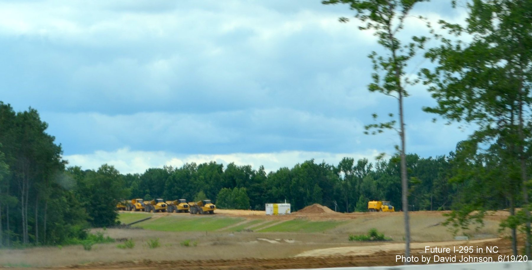 Image of construction vehicles parked along graded future I-295 North lanes from I-95 North near Hope 
        Mills, taken by David Johnson June 2020