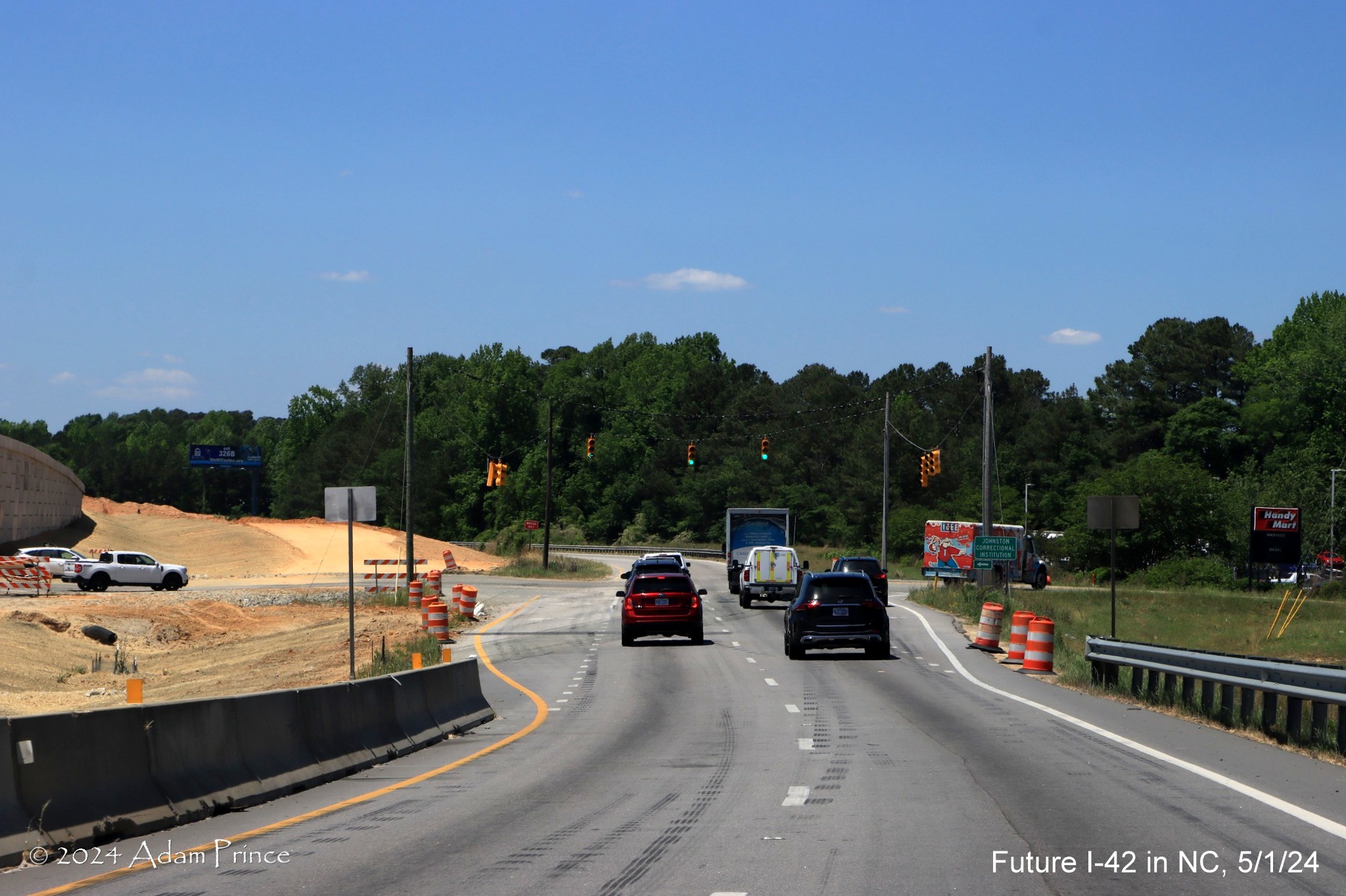 Image of US 70 (Future I-42) West traffic approaching traffic signals at Wilson's Mills Road 
        intersection, by Adam Prince, May 2024