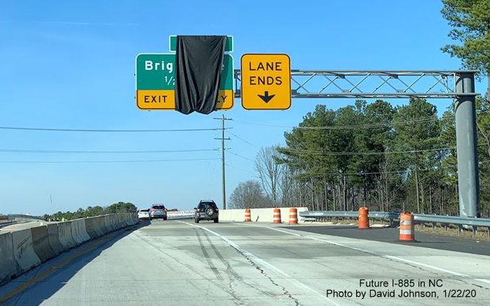 Image of 1/2 mile advance overhead sign for Briggs Road exit partially covered by a black tarp on NC 147 North in Durham, by David Johnson