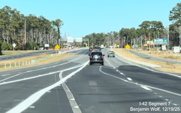 Image of West Business US 70 traffic merging with lanes at the western end of
	the US 70 (Future I-42) Havelock Bypass, Screen grab from Benjamin Wolf video, December 2025