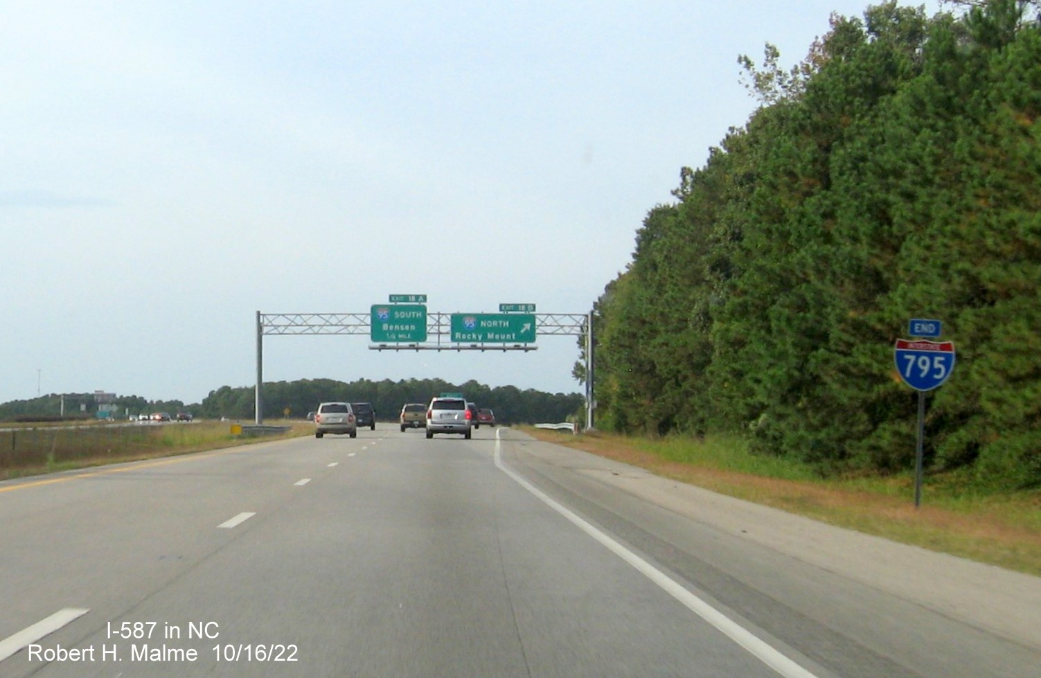 Image of End I-795 sign in front of overhead signs for I-95 exits with new I-587 exit numbers on I-587 West/I-795 North in Wilson, taken from opposite lanes, Google Maps Street View, August 2022