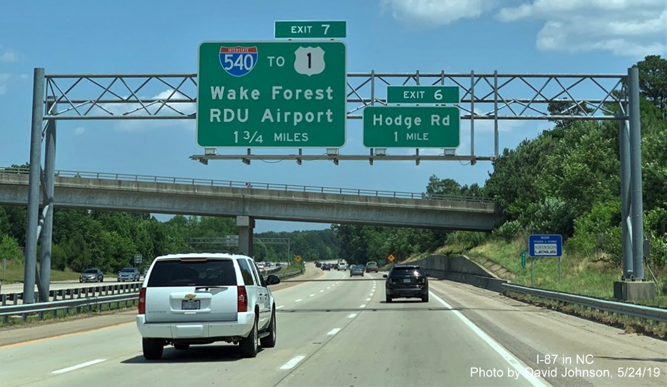 Image of overhead signs with new I-87 exit numbers approaching Hodge Road exit on I-87 North, US 64/264 East in Knightdale, by David Johnson