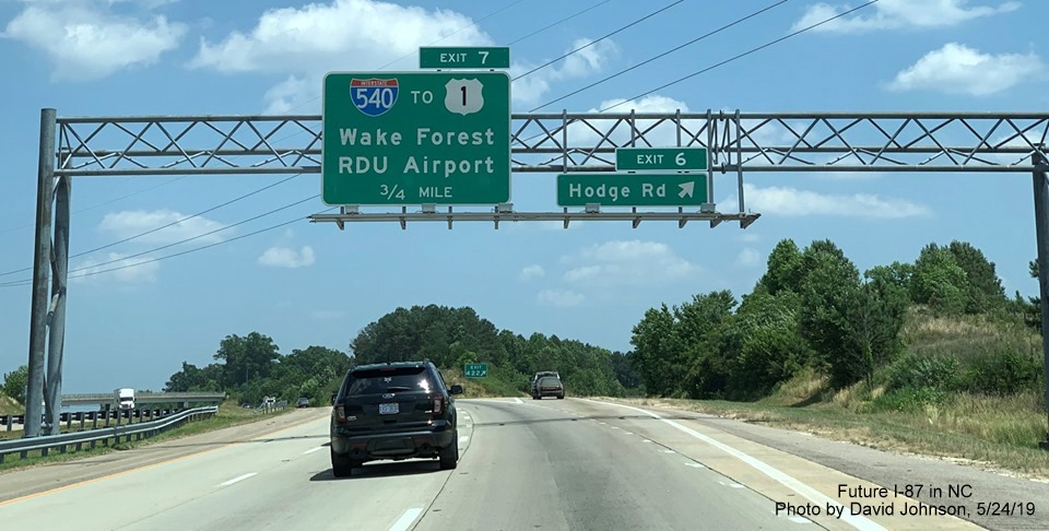 Image of overhead signs with new I-87 exit number tabs at off-ramp to Hodge Road on I-87 North, US 64/264 East in Knightdale, by David Johnson