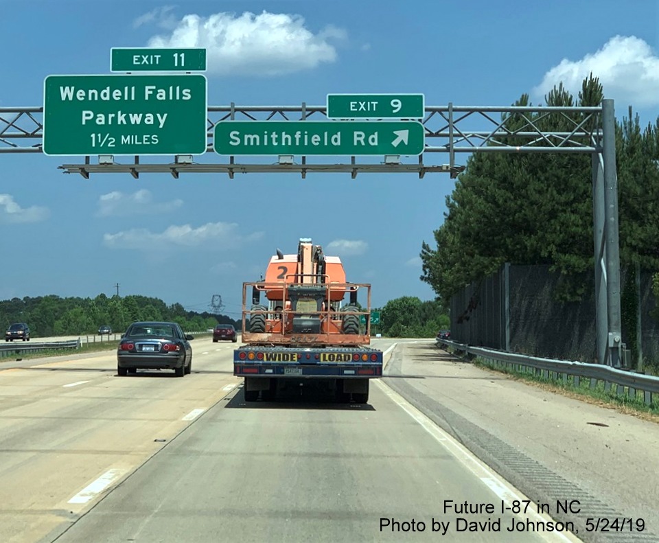 Image of overhead signs with new I-87 exit number tabs at Smithfield Road exit on I-87 North, US 64/264 East in Knightdale, by David Johnson